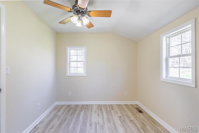 spare room with light wood-style flooring, vaulted ceiling, baseboards, and a ceiling fan