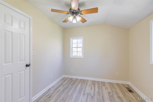 spare room featuring light wood-style flooring, a ceiling fan, vaulted ceiling, and baseboards