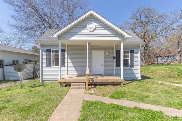 bungalow-style home featuring a front lawn, a shingled roof, and a porch
