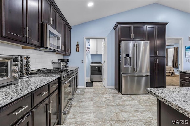 1869 Sunset Rdg, Festus, MO 63028 - kitchen featuring stainless steel appliances, vaulted ceiling, light stone counters, backsplash, and dark brown cabinetry