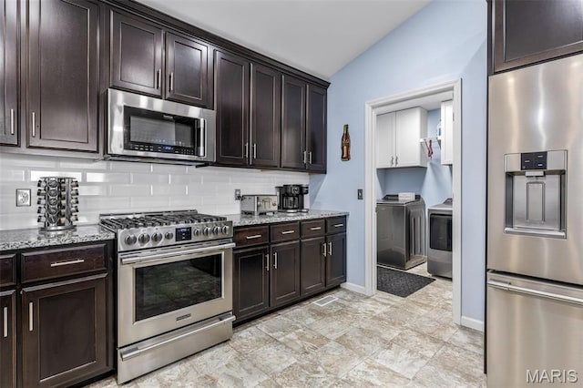 1869 Sunset Rdg, Festus, MO 63028 - kitchen featuring stainless steel appliances, washing machine and clothes dryer, light stone countertops, backsplash, and vaulted ceiling