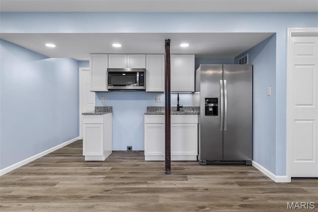1869 Sunset Rdg, Festus, MO 63028 - kitchen with stainless steel appliances, white cabinets, recessed lighting, wood finished floors, and baseboards