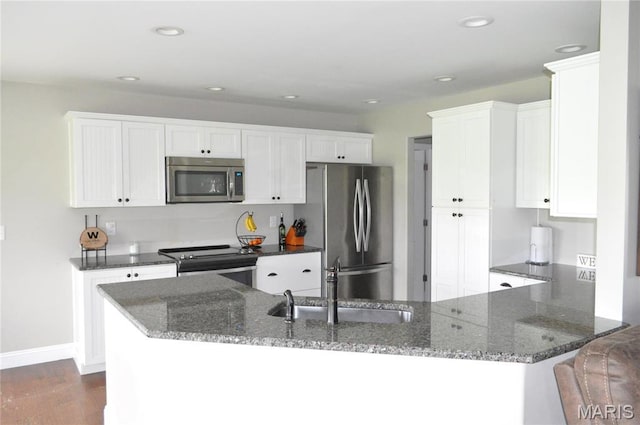 869 Destiny Dr, Villa Ridge, MO 63089 - kitchen featuring stainless steel appliances, dark stone counters, white cabinetry, dark wood finished floors, and recessed lighting