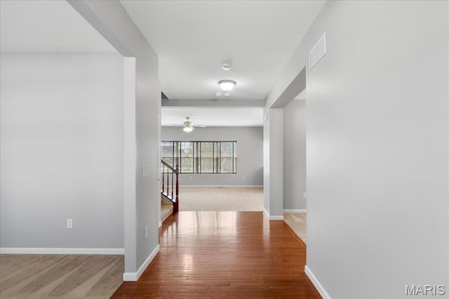 corridor featuring stairs, wood finished floors, and baseboards