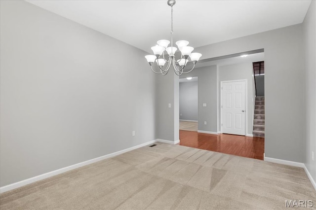 empty room with carpet floors, stairs, a chandelier, and baseboards