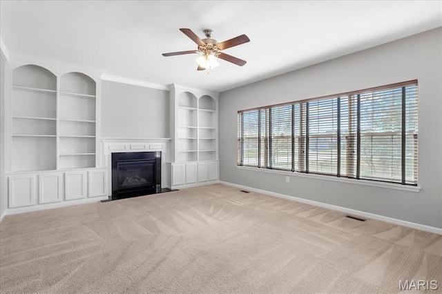 unfurnished living room with baseboards, carpet, a fireplace with flush hearth, ceiling fan, and built in features