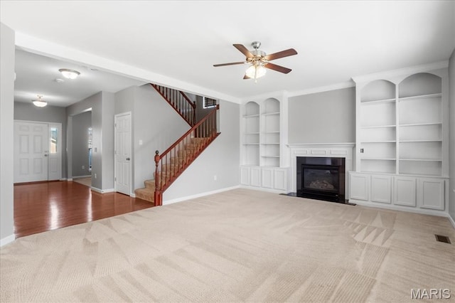 unfurnished living room featuring carpet, baseboards, stairway, and a fireplace with flush hearth