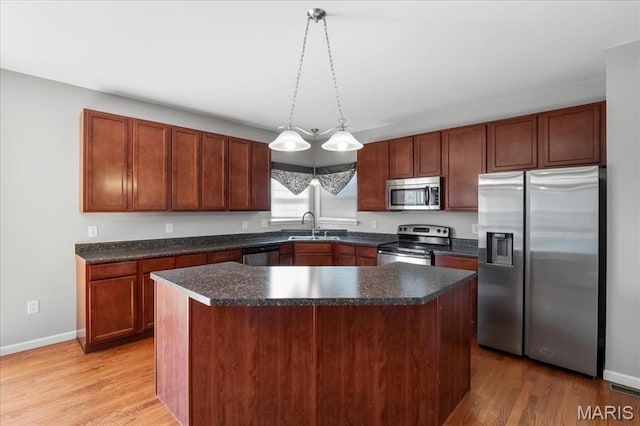 kitchen with appliances with stainless steel finishes, a sink, baseboards, and light wood-type flooring