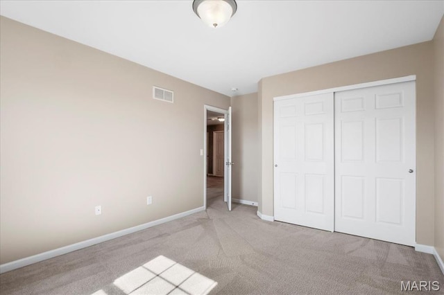 unfurnished bedroom featuring light carpet, baseboards, and a closet