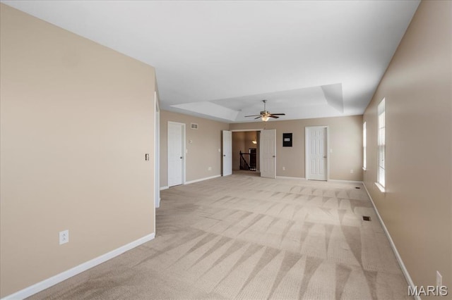 spare room with light carpet, baseboards, ceiling fan, and a tray ceiling