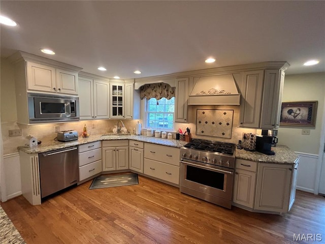 1843 Manor Hill Rd, Saint Louis, MO 63131 - kitchen with stainless steel appliances, premium range hood, backsplash, light wood-style flooring, and recessed lighting