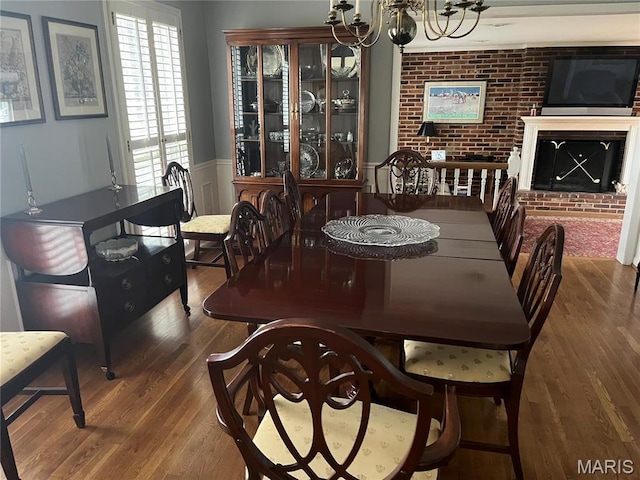 1843 Manor Hill Rd, Saint Louis, MO 63131 - dining space featuring a chandelier, wood finished floors, wainscoting, a brick fireplace, and brick wall