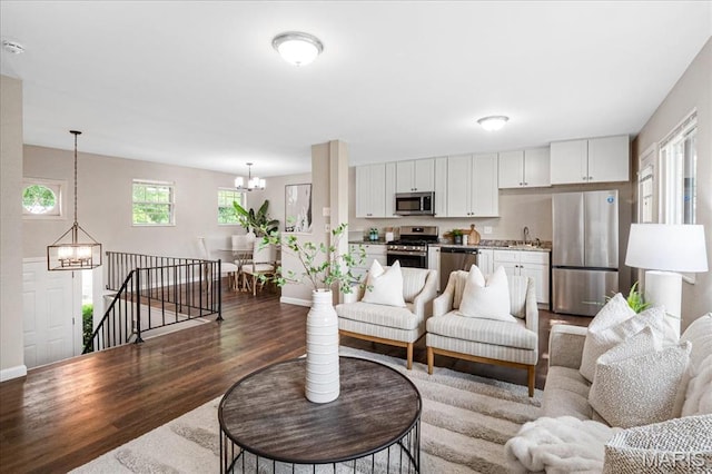 2145 Glenoro Dr, Florissant, MO 63033 - living area with a chandelier, dark wood-style floors, and baseboards