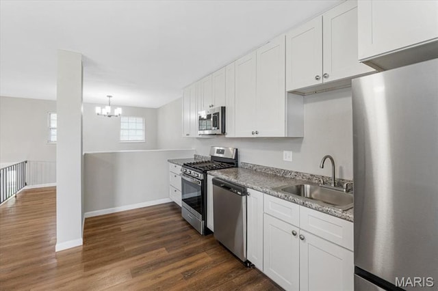 2145 Glenoro Dr, Florissant, MO 63033 - kitchen featuring appliances with stainless steel finishes, a sink, dark wood-style flooring, white cabinetry, and a chandelier
