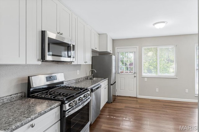 2145 Glenoro Dr, Florissant, MO 63033 - kitchen with stainless steel appliances, wood finished floors, white cabinets, a sink, and baseboards