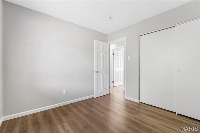 2145 Glenoro Dr, Florissant, MO 63033 - unfurnished bedroom with wood finished floors, baseboards, and a closet