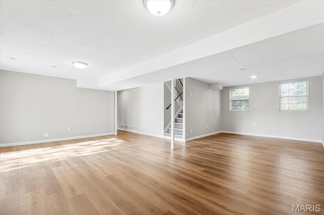 2145 Glenoro Dr, Florissant, MO 63033 - basement featuring a textured ceiling, stairs, light wood-type flooring, and baseboards