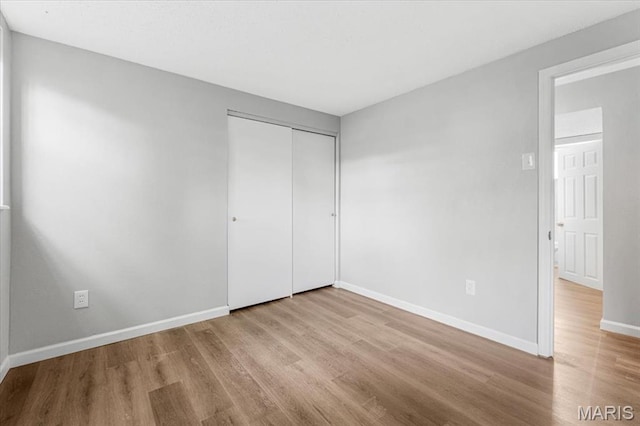 2145 Glenoro Dr, Florissant, MO 63033 - unfurnished bedroom featuring wood finished floors, baseboards, and a closet
