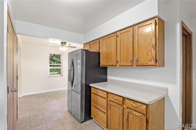 9506 B Rd, Valmeyer, IL 62295 - kitchen with light countertops, stainless steel refrigerator with ice dispenser, a ceiling fan, brown cabinets, and baseboards