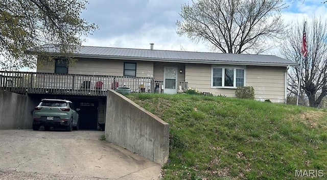 ranch-style home with driveway, metal roof, and an attached garage
