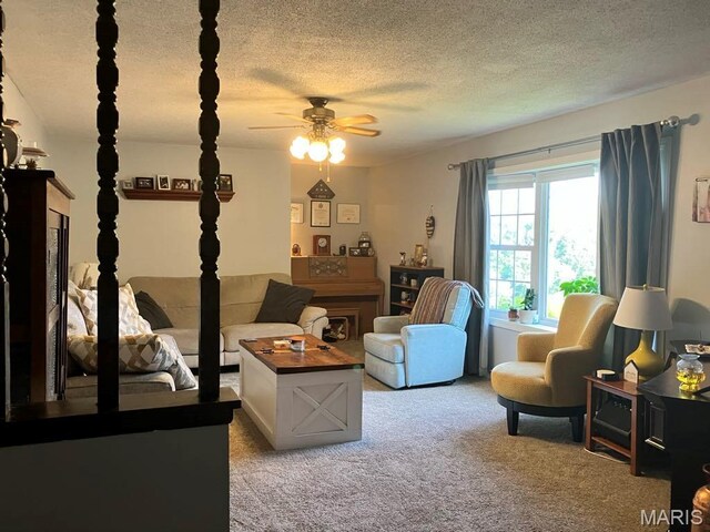 living area with a ceiling fan, light carpet, and a textured ceiling