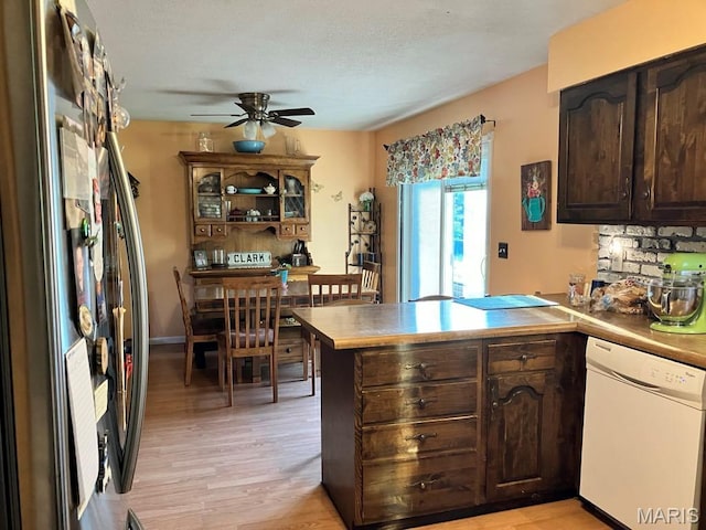 kitchen with dishwasher, freestanding refrigerator, a peninsula, dark brown cabinetry, and light wood-type flooring