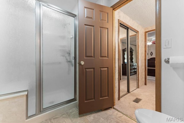 full bathroom featuring a shower stall and a textured ceiling