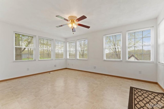 unfurnished room featuring a ceiling fan, baseboards, and light floors