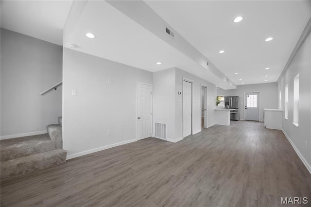 unfurnished living room with stairs, dark wood finished floors, baseboards, and recessed lighting