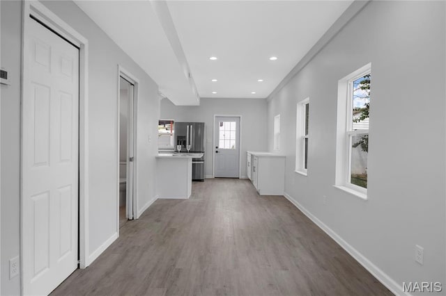 hallway with wood finished floors, baseboards, and recessed lighting