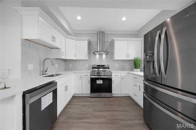 kitchen featuring appliances with stainless steel finishes, wall chimney exhaust hood, a sink, light countertops, and white cabinetry