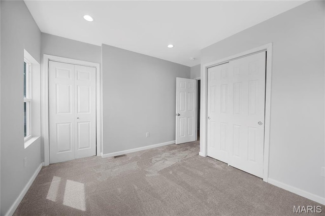 unfurnished bedroom with carpet flooring, baseboards, multiple closets, and recessed lighting
