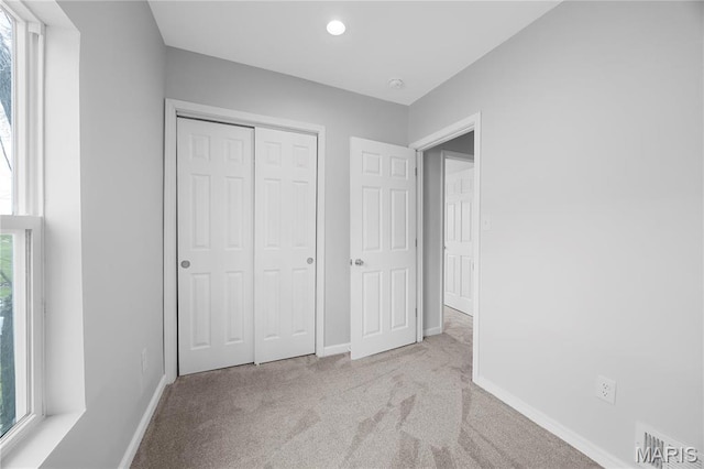 unfurnished bedroom featuring carpet, baseboards, a closet, and recessed lighting