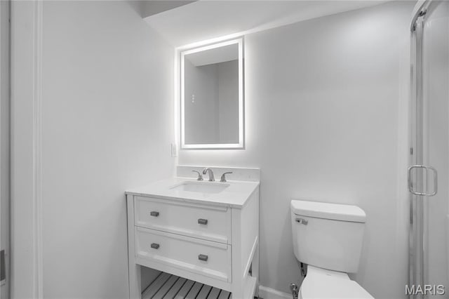 bathroom with toilet, vanity, and a shower with shower door