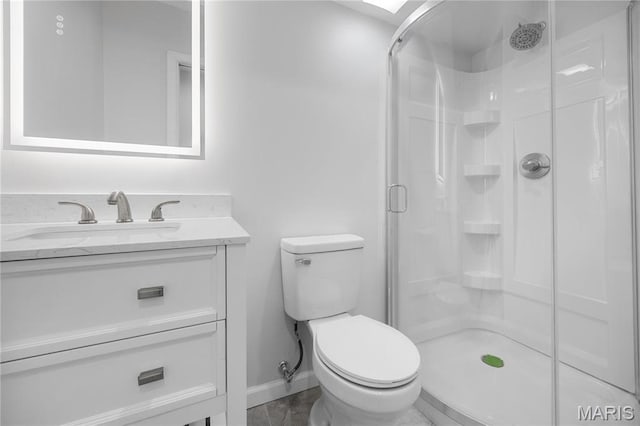 full bathroom with a stall shower, toilet, baseboards, and vanity
