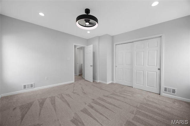 unfurnished bedroom featuring carpet, baseboards, recessed lighting, and a closet