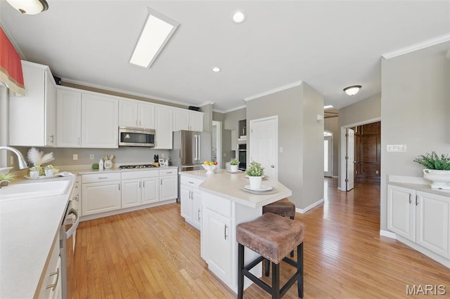 kitchen featuring appliances with stainless steel finishes, a sink, a kitchen breakfast bar, crown molding, and a center island
