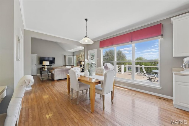 dining area with light wood-style floors, crown molding, and baseboards