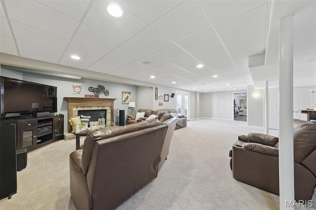 living room with light carpet, a drop ceiling, a fireplace with raised hearth, and recessed lighting