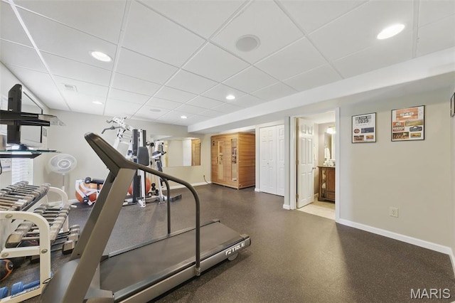 exercise room featuring baseboards, a drop ceiling, and recessed lighting