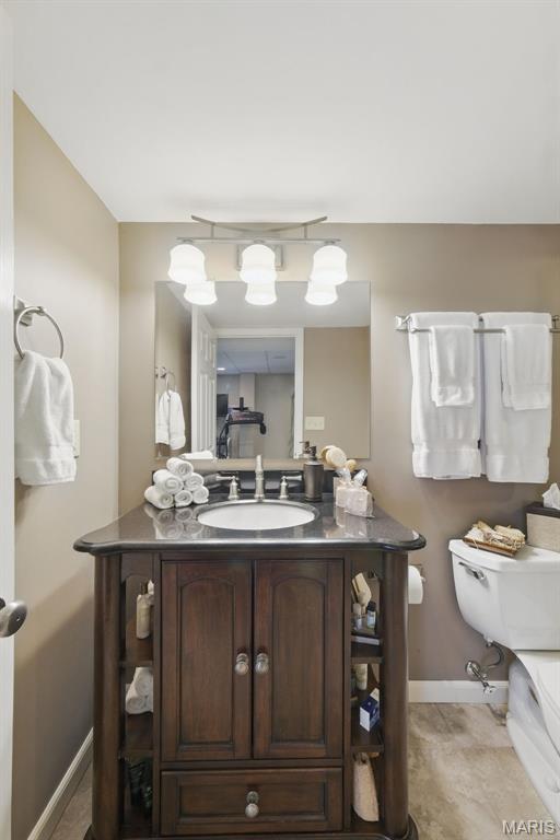 bathroom featuring baseboards, toilet, and vanity