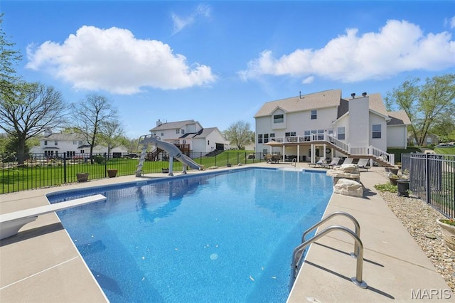 view of swimming pool with a water slide, stairway, a diving board, a patio area, and a deck