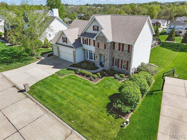 view of front of home featuring stone siding, concrete driveway, a garage, a front lawn, and a residential view