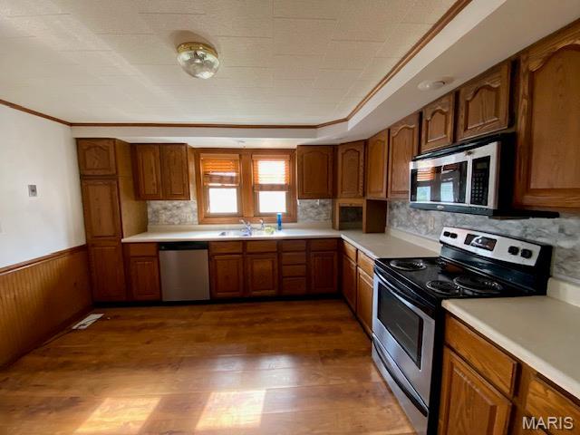 kitchen featuring appliances with stainless steel finishes, dark wood finished floors, brown cabinets, light countertops, and backsplash