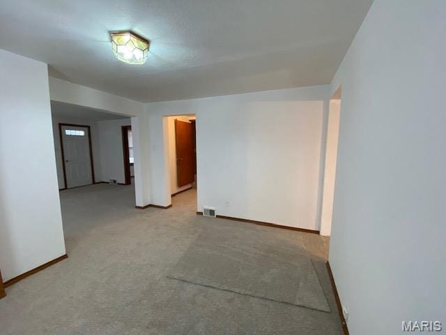 spare room featuring baseboards and light carpet