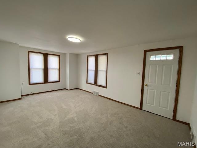 spare room featuring baseboards and light colored carpet