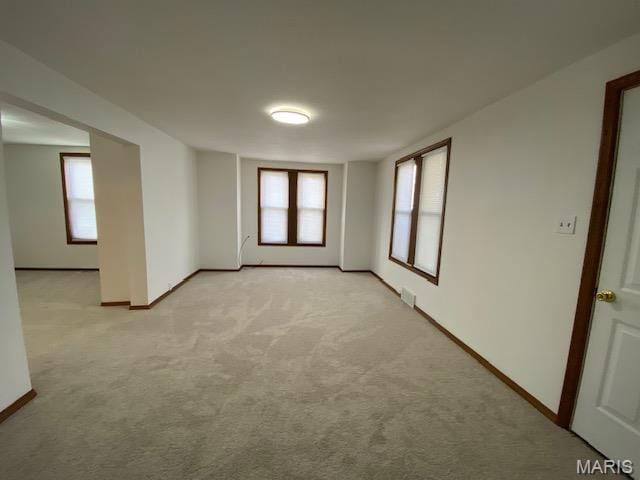 spare room with light colored carpet, plenty of natural light, and baseboards