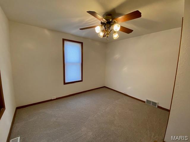 carpeted spare room featuring a ceiling fan and baseboards