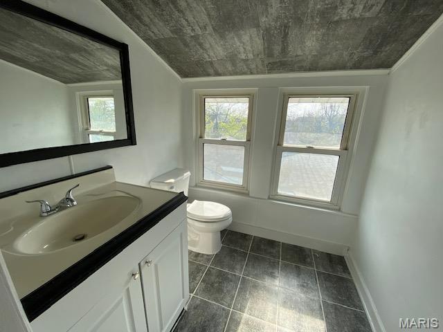 bathroom featuring healthy amount of natural light, toilet, vanity, and tile patterned floors