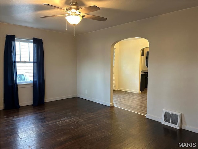 127 Whitelaw Ave, East Alton, IL 62024 - unfurnished room featuring arched walkways, a ceiling fan, dark wood finished floors, and baseboards